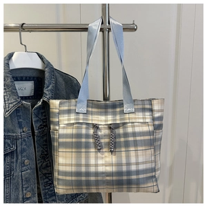 Close-up of blue plaid canvas tote bag featuring decorative drawstring knot and webbing handles