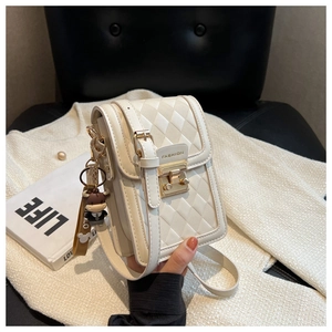 Close-up of white quilted mobile phone bag with gold clasp and small calf pendant