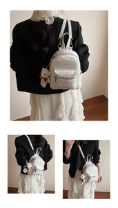 Detalle de mini mochila de cuero PU blanco con colgante de oso y cremalleras plateadas