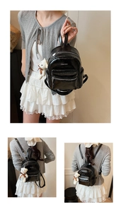 Detalle de la mini mochila de charol negro con colgante de osito de peluche suave