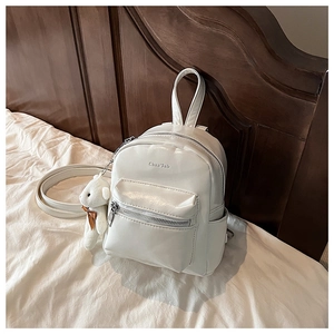 Detalle de una mini mochila de cuero PU blanco roto con un colgante de oso de peluche