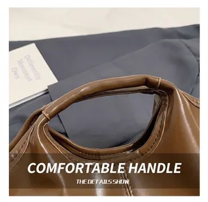 Close-up of the smooth integrated leather handle with refined stitching on the brown tote