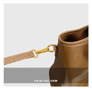 Close-up of durable golden metal hook and brown leather strap connection on the bag