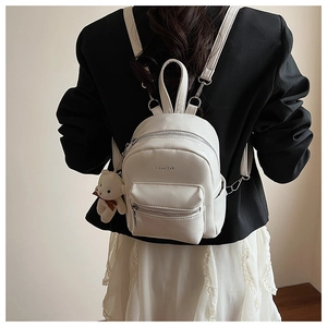Vista trasera de una mini mochila de cuero PU blanco con un colgante de oso café