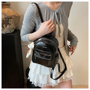 Detalle de mini mochila de cuero PU negro brillante con colgante de oso blanco