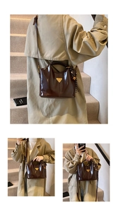 Detail of dark brown patent leather handbag with gold triangle buckle and fringe charm