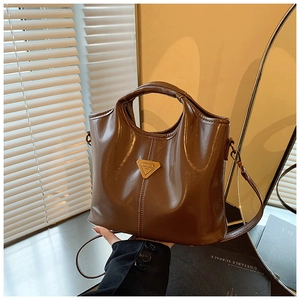 Detail of dark brown glossy leather handbag featuring golden triangle logo and fine stitching