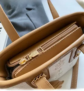 Close-up of smooth gold metal zipper and stitching on brown leather bucket bag