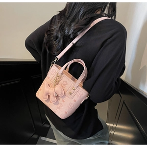 Detail of pink embossed bucket bag with dog charm and starry floral pattern textures