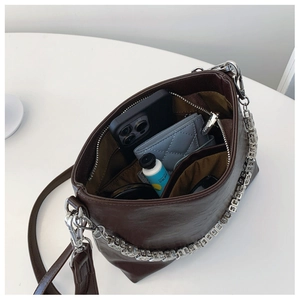 Internal view of a brown bucket bag showing capacity for phone, cards and cosmetics