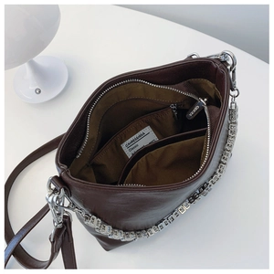 Top-down view of the deep brown bucket bag interior with zipper pocket and silver chain