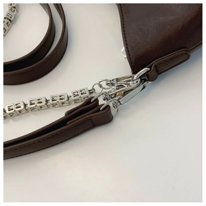 Macro shot of silver-tone metal 4G logo chain and hardware on dark brown leather bag