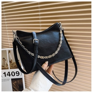 Close-up of black bucket bag featuring textured faux leather and silver G-link chain detail