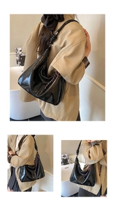 Détail du sac hobo noir brillant avec bandoulière à nœud tressé et texture élégante