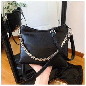 Close-up of black leather bucket bag featuring silver G-link chain and metal zipper details