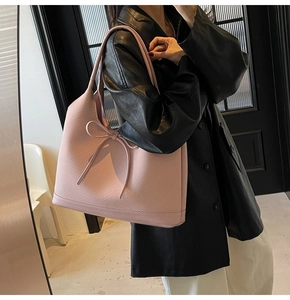 Detail of light pink tote bag with diagonal woven texture and bow accent on shoulder