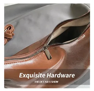 Détail de la fermeture éclair métallique et du cuir ciré vintage du sac marron