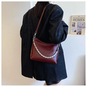 Detail view of burgundy leather hobo bucket bag with silver chain and shoulder strap