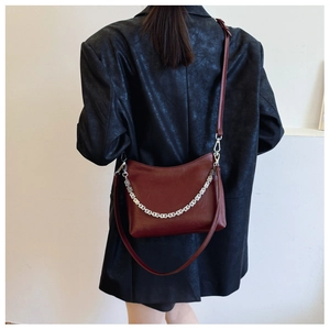 Deep burgundy leather bucket bag with silver chain detail on model wearing black jacket