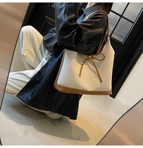 Mirror reflection view of a canvas tote bag with brown leather bow and strap detail
