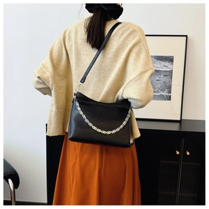 Lifestyle view of a black leather shoulder bag with an iconic silver G-link chain detail