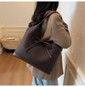 Close-up of woven canvas tote bag featuring brown leather trim and bow detail