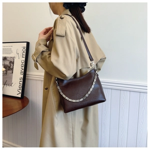 Detail of dark brown leather crescent bag featuring a stylish silver block chain strap