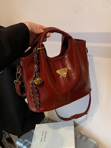 Vintage burgundy tote bag with gold metal logo and decorative charm for travel