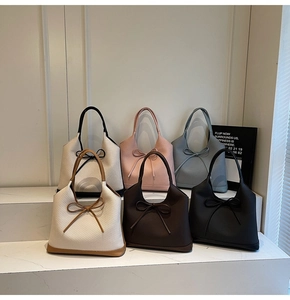 Detail shot of textured leather tote bags in multiple colors with bow decorative accents