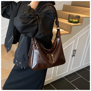 Détail du sac hobo marron foncé brillant avec sangle nouée et breloque assortie
