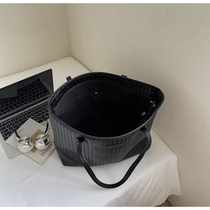 Close-up of black woven tote bag interior with office essentials on white desk
