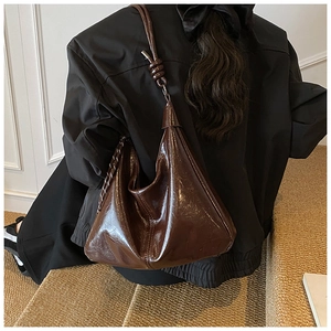 Détail du sac cabas en cuir verni marron foncé avec une bandoulière nouée élégante