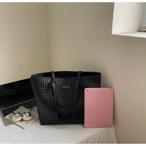 Detail of black woven tote bag showing large capacity for laptops and daily essentials