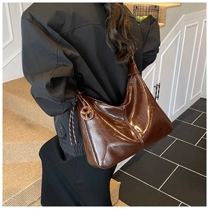 Détail d'un sac hobo marron en cuir huilé brillant avec des détails de corde tressée