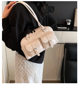 Detail of a cream faux leather shoulder bag with double flap pockets and silver hardware