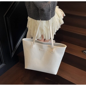 Detailed close-up of white woven leather tote bag with metallic ZSKE PARIS logo plate