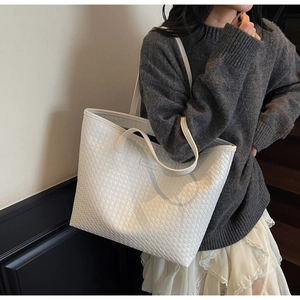 Detail of white woven tote bag featuring the Zeke Paris logo patch and slim shoulder straps