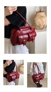 Detail view of deep red oil wax leather shoulder bag with functional buckled front pockets
