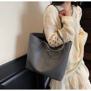Close-up of gray woven leather tote bag with brand logo and detailed texture