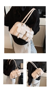 Detail view of cream patent leather shoulder bag with decorative buckle pockets on the front