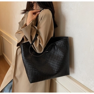 Side view of large black woven tote bag with leather straps on a model for daily commute