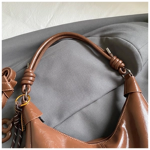 Détail du sac hobo marron foncé avec bandoulière nouée et cuir ciré brillant