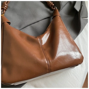 Détail du sac rétro en cuir marron avec bandoulière nouée et texture plissée élégante