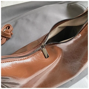 Détail du sac à bandoulière marron avec fermeture éclair et doublure à chevrons beige
