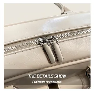 Close-up of dual silver zippers and lychee texture on cream leather shoulder bag