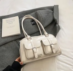 Detail shot of white patent leather handbag with metal buckle pockets on grey coat
