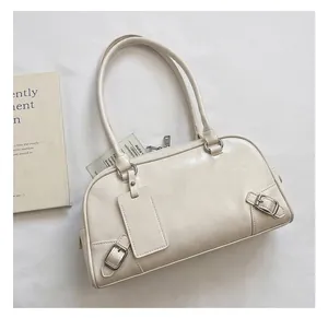 Detail view of large cream leather pillow bag with stylish round top handles and rings