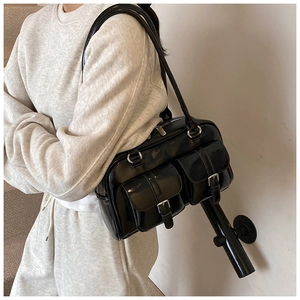 Detailed view of black patent leather shoulder bag with dual buckle pockets and silver hardware