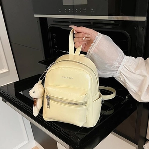 Mini mochila color crema estilo preppy con dije de oso de peluche y acabado brillante diario