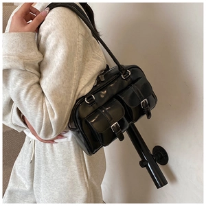 Detail showing high-shine black leather texture and silver buckle pockets on the shoulder bag